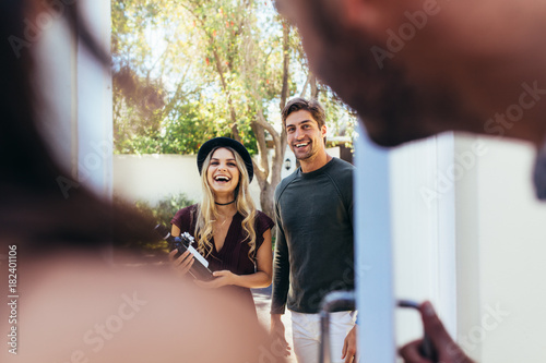 Foto Smiling young couple at entrance door with wine bottle
