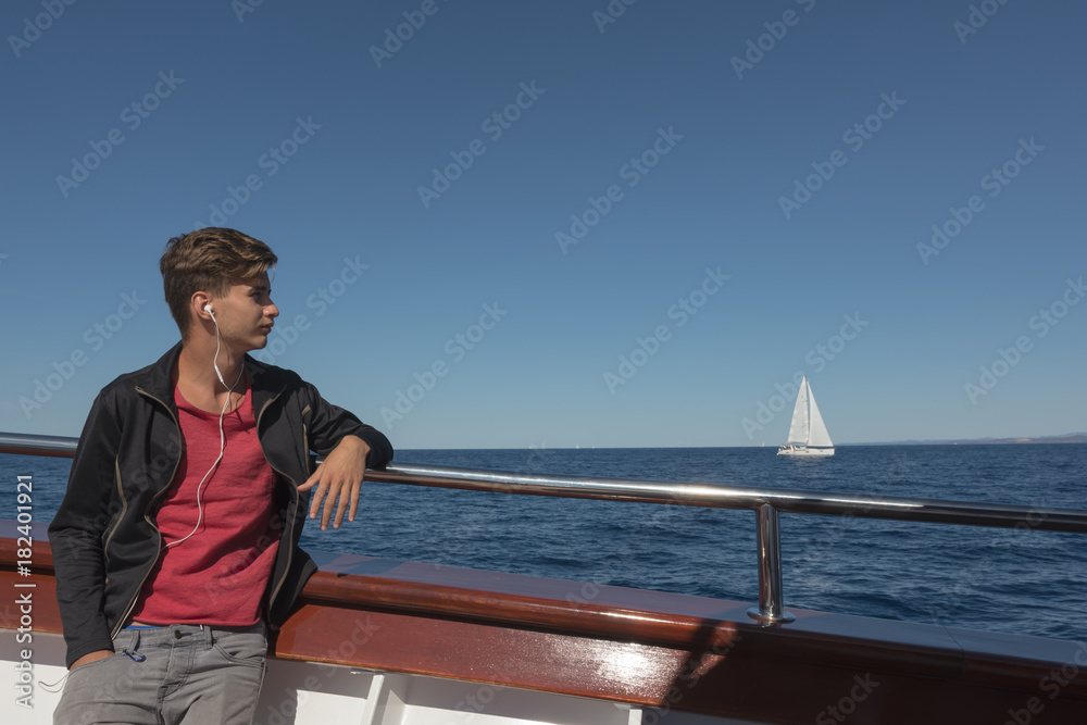 Teen boy listens to music in headphones and travels on the Adriatic Sea