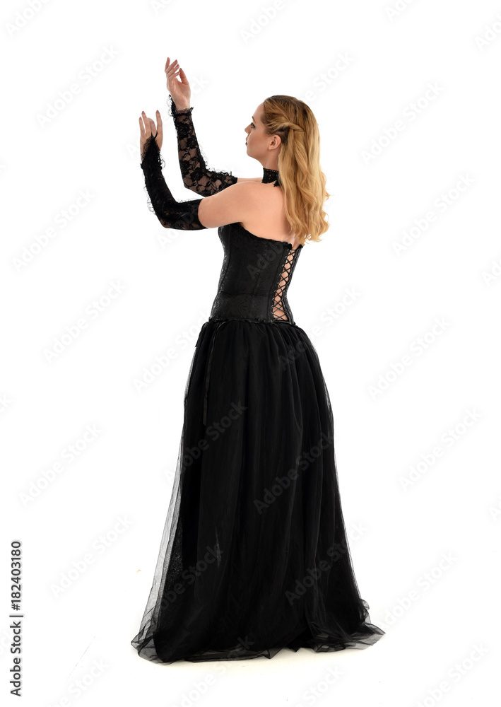 full length portrait of a blonde girl wearing black gothic gown. standing pose, isolated on white background. full length portrait of a blonde girl wearing black gothic gown. standing pose, isolated on white background.