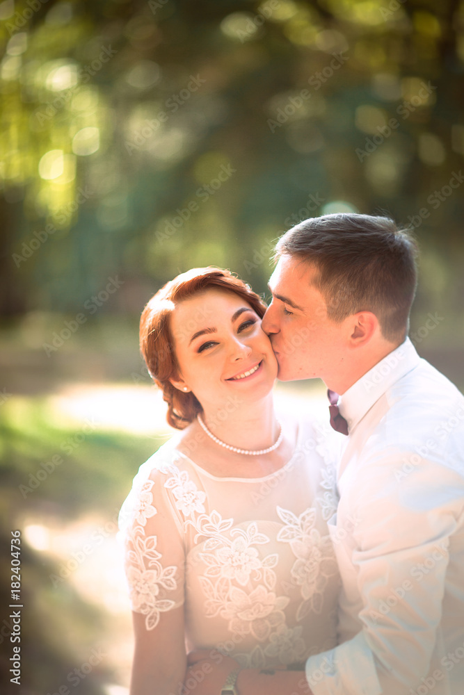 Fototapeta premium The bride and groom in the background of park trees