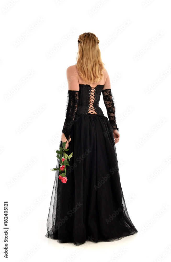 full length portrait of a blonde girl wearing black gothic gown. standing pose, isolated on white background.