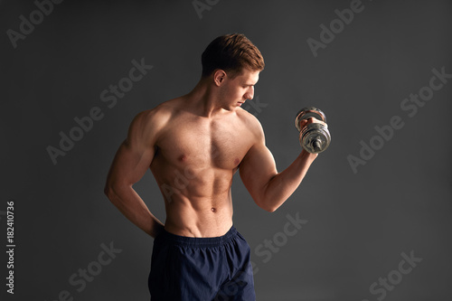 Handsome sportsman training bicep in studio © kegfire
