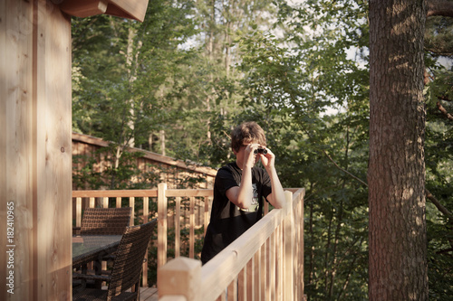 Boy looks through binoculars from the balcony of the treehouse hotel, Rosenberg near Ellwangen, Aalen, Ostalbkreis, Baden-Wuerttemberg, Germany photo