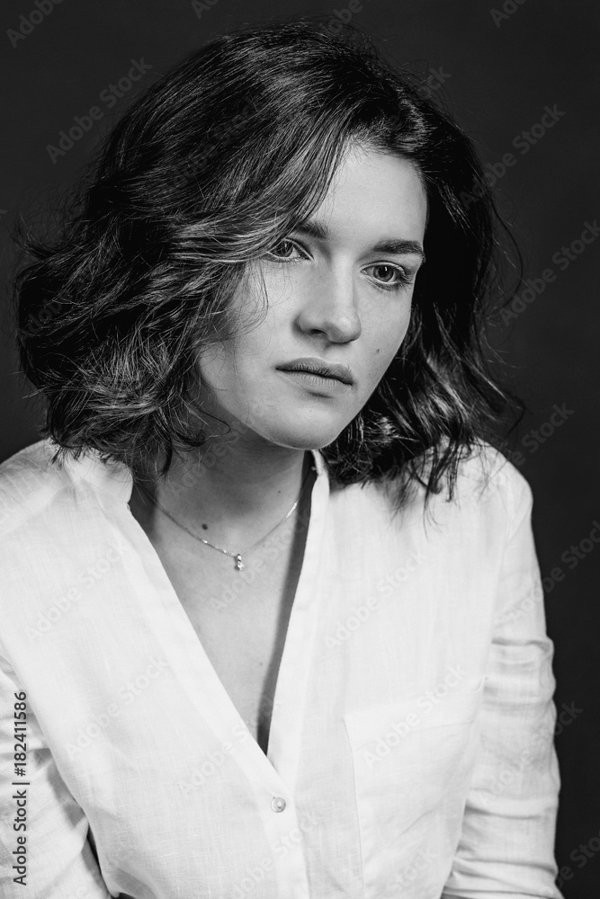 Black and white portraite of young, beautiful sad woman actress with short brown hair in the studio