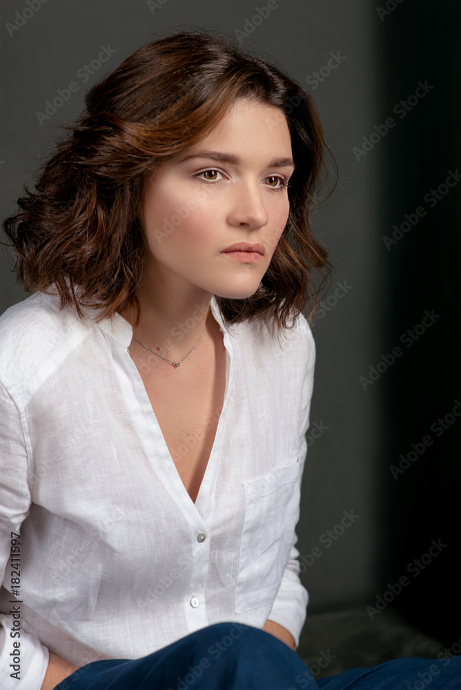 Foto Stock Portraite of young, beautiful sad woman actress with short brown  hair in white shirt and blue pants in the studio | Adobe Stock