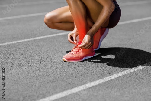 Low section of athlete tying shoelace on track