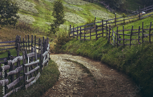 Dirt road and rustic wooden fences in a traditional Transylvanian village, Brasov county, Romania.