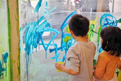 壁に絵の具で絵を描く子供たち