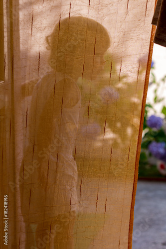 Little girl on the balcony behind the courtain