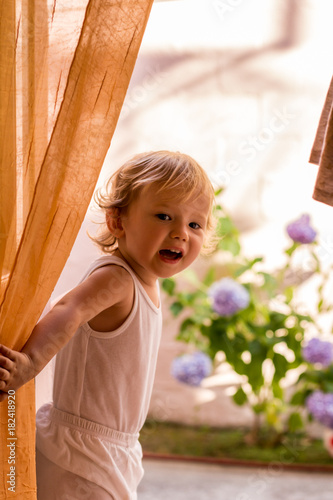 Little girl on the balcony behind the courtain