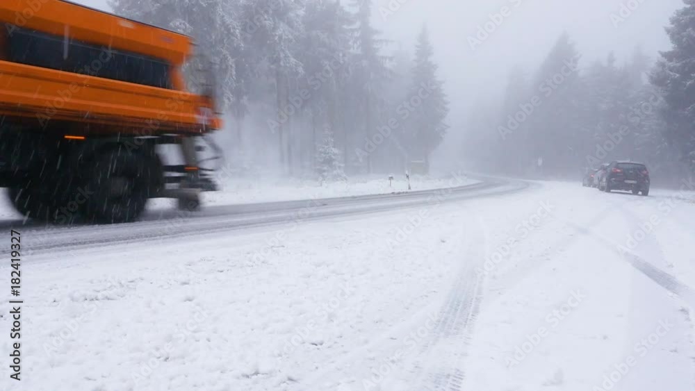 A truck snowplow is clearing the road of snow on a federal street in the Taunus area in Germany A truck snowplow is clearing the road of snow on a federal street in the Taunus area in Germany