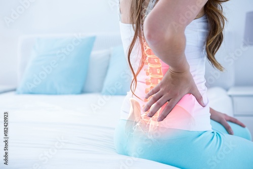 Digital composite of highlighted spine of woman with back pain