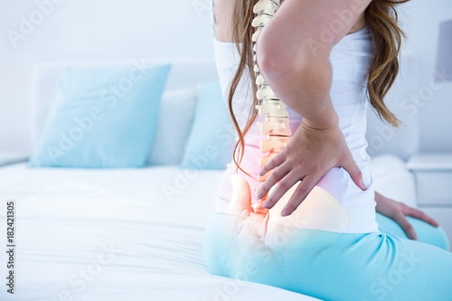 Digital composite of highlighted spine of woman with back pain photo