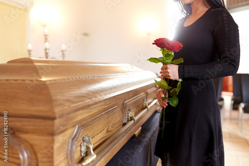 woman with red roses and coffin at funeral photo
