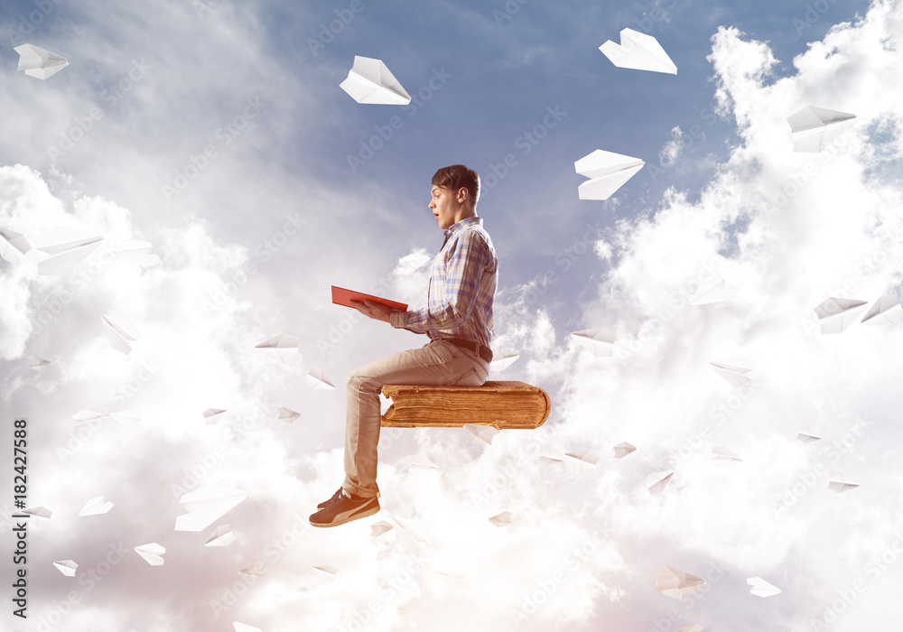 Handsome man student reading book and paper planes flying around Handsome man student reading book and paper planes flying around