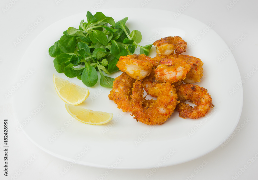 Fried shrimps on a plate. Prawns fried in breading on a white plate with salad and lemon. Fried shrimps on a plate. Prawns fried in breading on a white plate with salad and lemon.