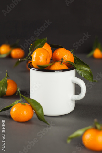 mandarins tangerine in a white mug on a dark gray background - healthy vegan vegetarian food, raw diet