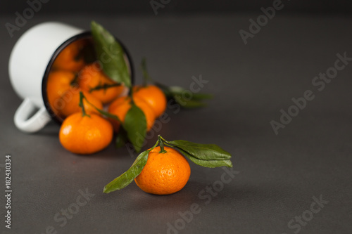 mandarins tangerine in a white mug on a dark gray background - healthy vegan vegetarian food, raw diet