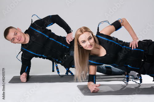 Young man and a woman in an electric muscular suit are trained to stimulate themselves