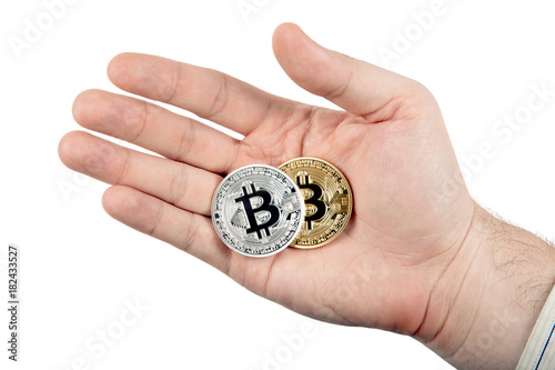 two coins of bitcoin in the hand of a man on a white background
