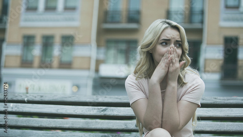 Sad young lady sitting alone and crying bitterly, relationship or health problem