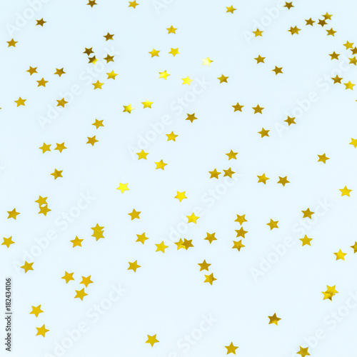 Golden star sprinkles on blue. Festive holiday background. Celebration concept