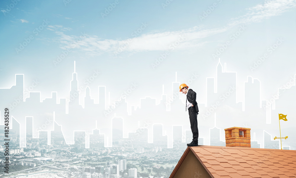 Engineer man standing on roof and looking down. Mixed media Engineer man standing on roof and looking down. Mixed media