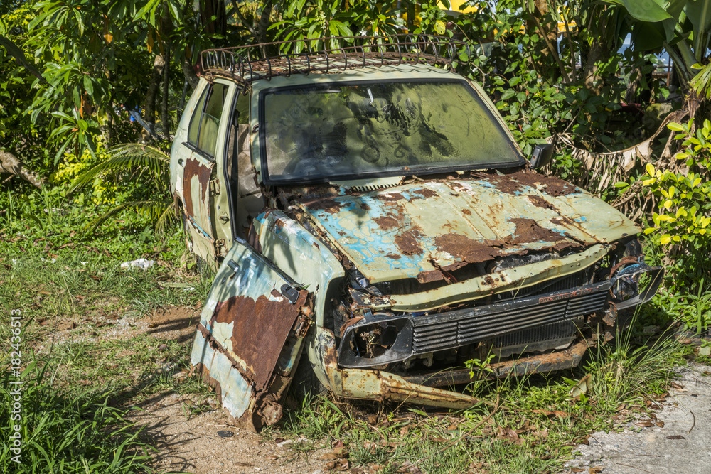 Rusty car abandoned near tropical palm trees Rusty car abandoned near tropical palm trees
