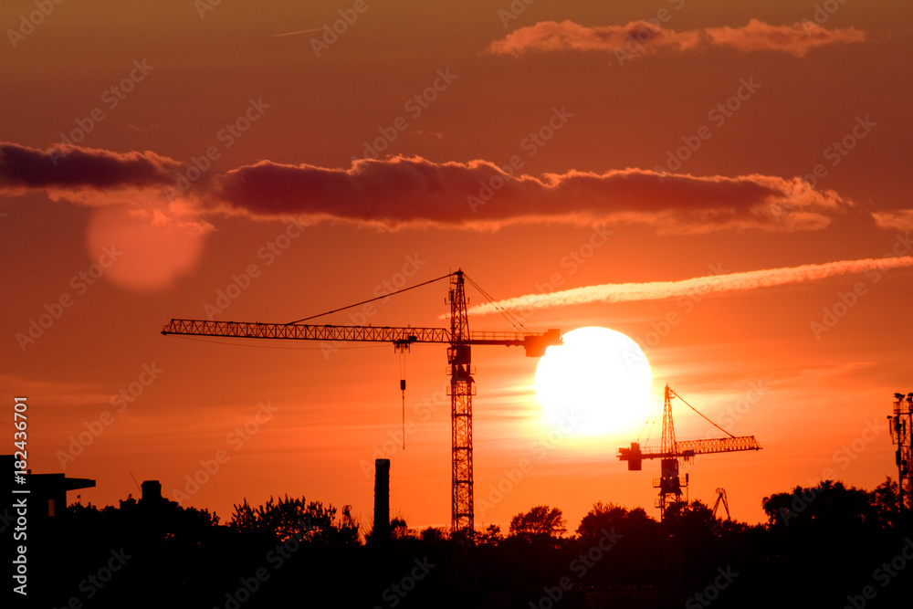 Construction crane on sunset city landscape