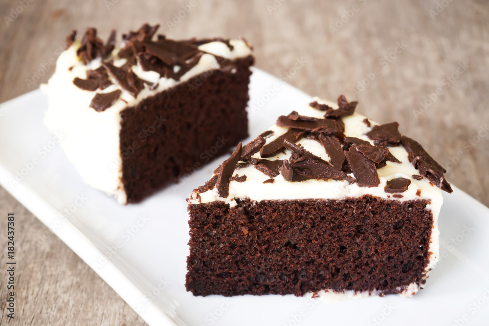 Sliced Chocolate cake decorate with whipping cream, sliced chocolate on white plate. Sweet dessert for celebrate.