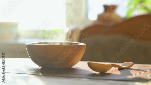 hot soup in a wooden plate. next to the table is a wooden spoon
