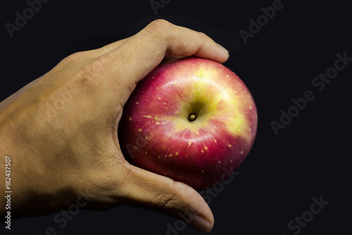 hand touching red apple isolated on black bg with luxury tone