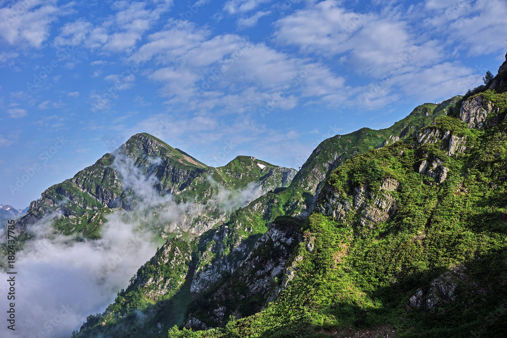 Panorama of the mountains in the area of Krasnaya Polyana/Panorama of Sochi in the Krasnaya Polyana area. There are mountains, clouds, air haze, vegetation. Sochi, Russia, mountain landscape 