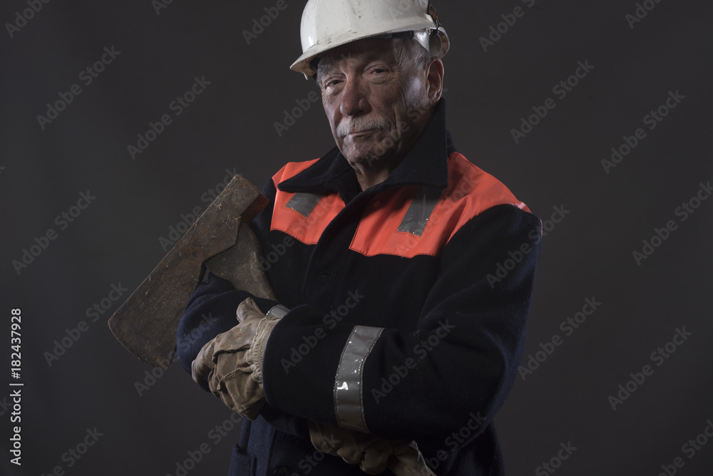 Mature miner covered in coal dust holding an axe 