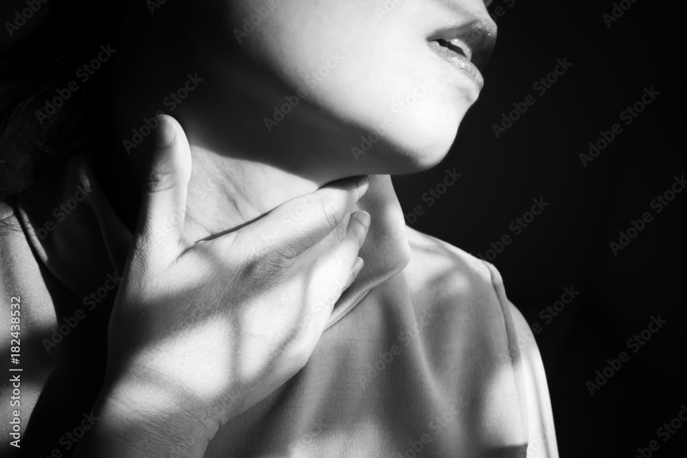 Closeup woman hand touching on neck. Sore throat. Primary symptoms of colds. Black and white theme.