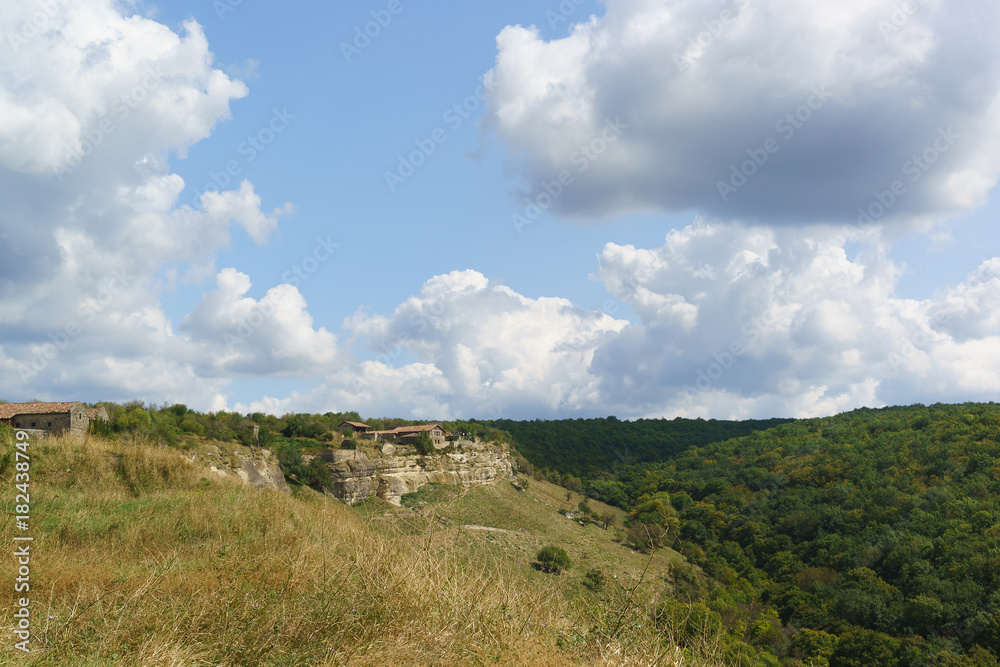 The old buildings above the natural boundary of Mariam-Dere near Bakhchisarai. Cave city Chufut-Kale in a Sunny day of early autumn