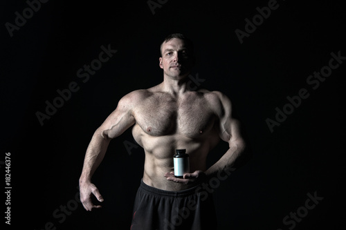 Man with muscular body hold pill jar, sport.