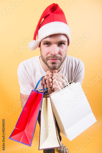 Man shopper in santa hat with paperbags
