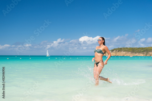 Woman in bikini run on beach in st johns, antigua
