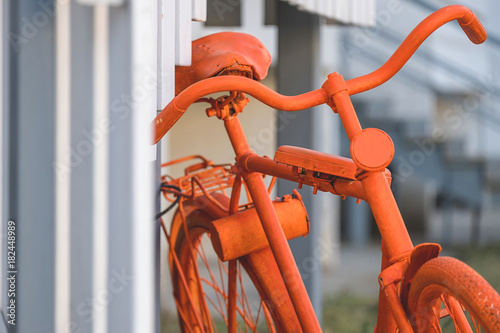 part of the orange bike standing near the wall of the house and stairs