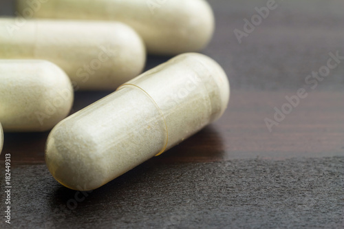 White capsules of glucosamine chondroitin, healthy supplement pills on wooden table, macro image