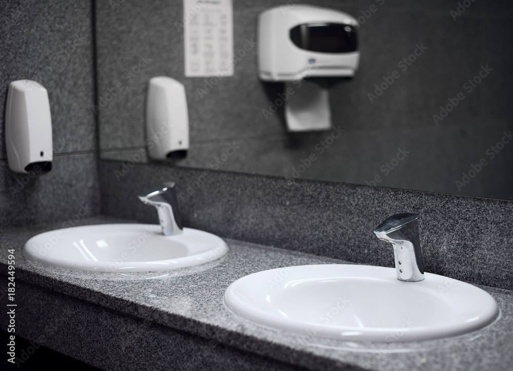 Fototapeta premium Empty public toilet room with sinks and taps.