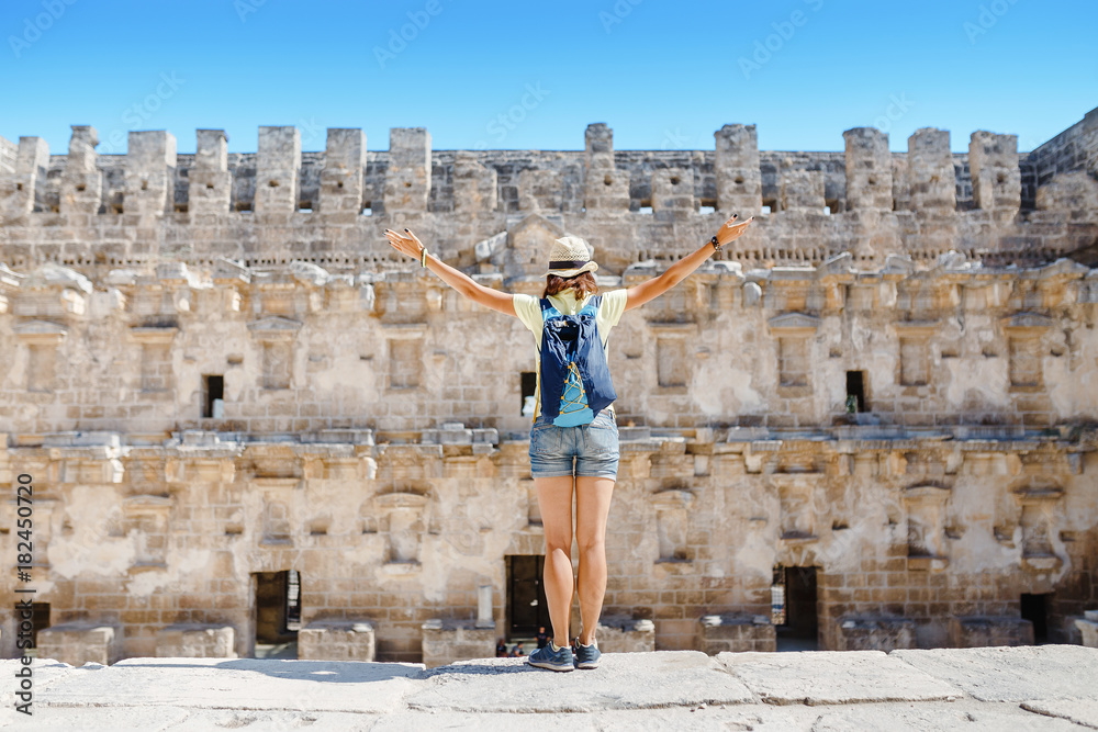 Happy woman traveler exploring the ruins of the ancient Greek amphitheater Aspendos in Turkey