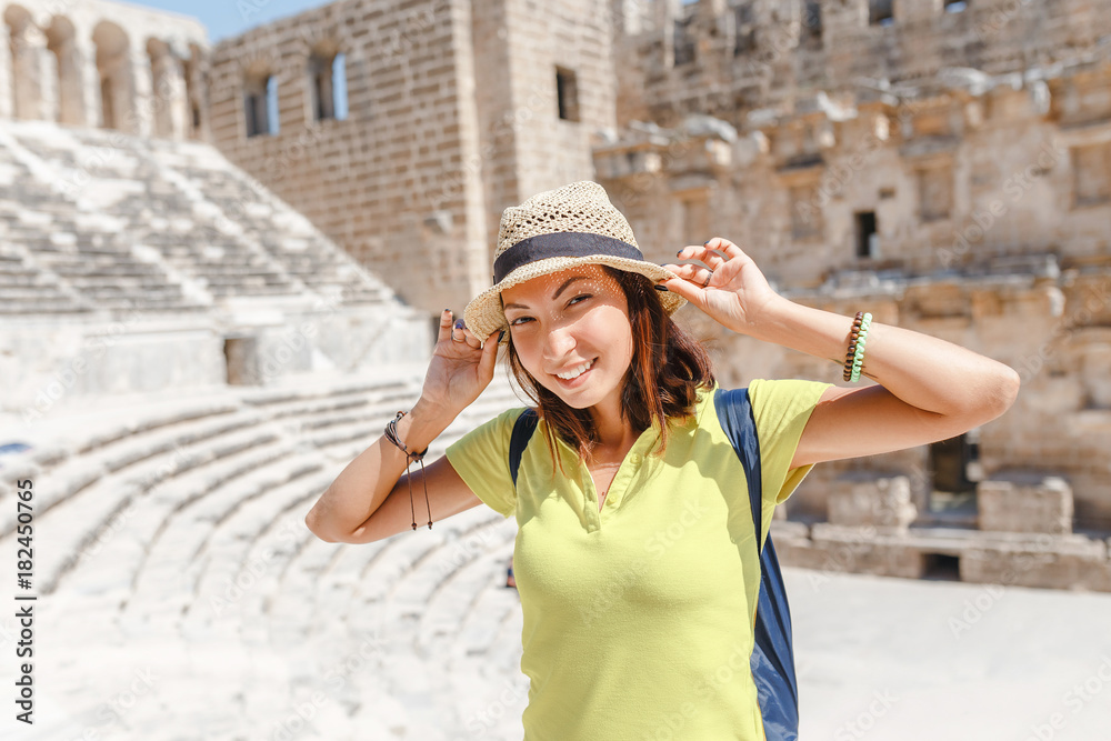 Happy woman traveler exploring the ruins of the ancient Greek amphitheater Aspendos in Turkey