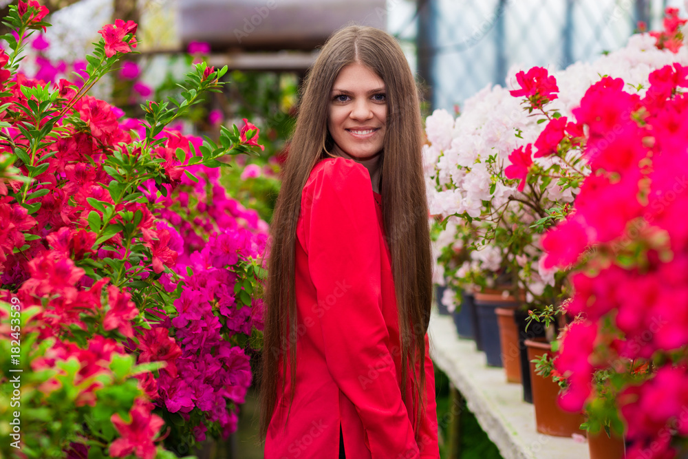 Happy young women with very long hair in a red blouse in a rose garden