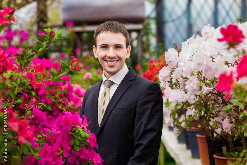 Attractive smiling young men in a business suit in a flower garden. Concept of a successful Attractive smiling young men in a business suit in a flower garden. Concept of a successful