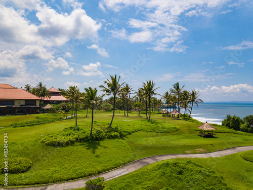 Golf club with green hills and many palm trees near Tanah lot temple, Bali island, Indonesia.