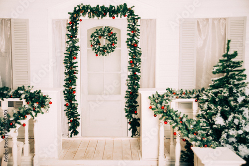house entrance decorated for holidays. Christmas decoration. garland of fir tree branches and lights on the railing