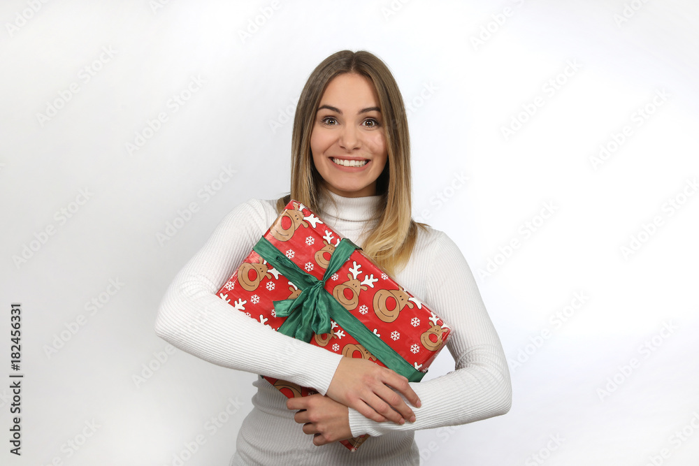 Hübsche blonde Frau mit Weihnachtsgeschenk im Arm freut sich Hübsche blonde Frau mit Weihnachtsgeschenk im Arm freut sich