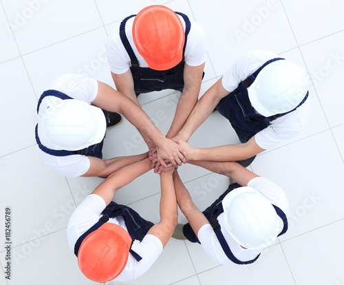 group of construction workers with hands clasped together